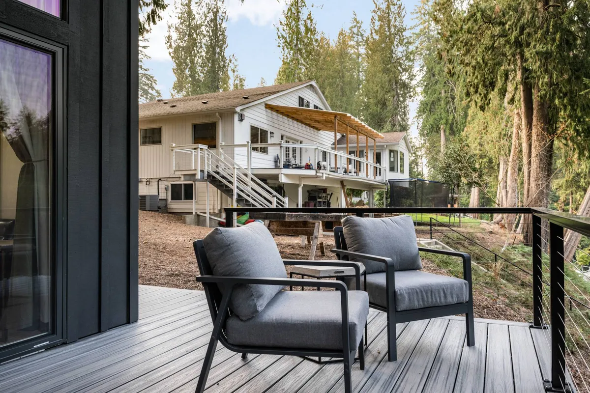 Deck chairs arranged on a wooden deck attached to the house, with a backdrop of surrounding trees. The inviting setup is perfect for relaxation, socializing, or quiet contemplation.