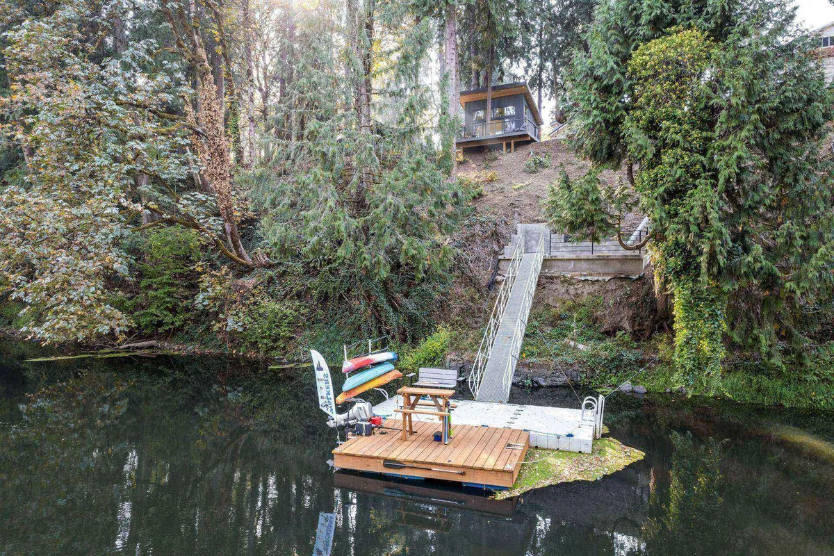 A floating dock set on calm water, featuring wooden chairs and steps that lead directly to the river. The scene is peaceful, with tranquil waters and a sense of serenity ideal for reflection or quiet outdoor activities.
